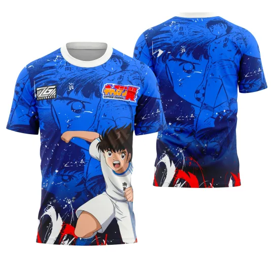 Camisa azul com gola branca apresenta personagem de anime Captain Tsubasa em uniforme branco na frente e versão ampliada do rosto em azul escuro nas costas, com detalhes em vermelho e textos em japonês e inglês.