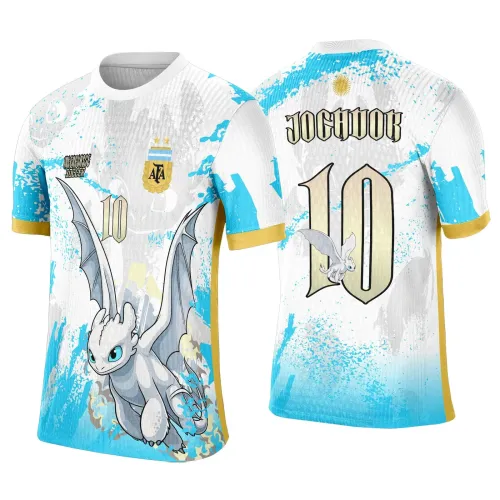 Camisa branca com detalhes em azul e dourado, dragão Banguela em pose dinâmica na frente, com número 10 e logo AFA. Nas costas, número 10 grande com texto JOGADOR e dragão pequeno na letra O, fundo com manchas azuis e grafite.
