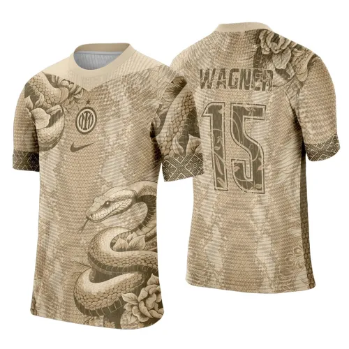 Camisa bege com cobra enrolada e flores na frente, logo do Inter no peito; nas costas o nome Wagner e número 15 em fonte com desenho floral, com padrão de escamas e detalhes geométricos nas mangas.