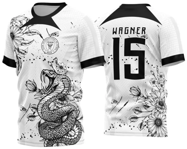 Camisa branca com gola preta, frente exibe uma cobra enrolada e flores em preto, escudo com texto do clube; costas mostram nome WAGNER, número 15 e detalhes florais pretos alinhados ao lado direito inferior.