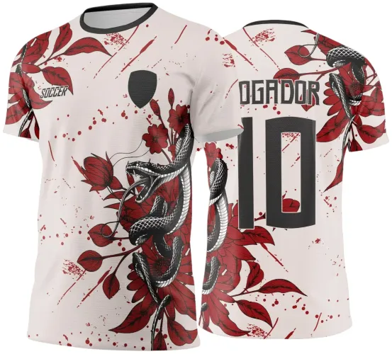Camisa branca com estampa de cobra preta enrolada em flores vermelhas na frente e costas, número 10 em preto nas costas, texto JOGADOR acima do número, detalhes em vermelho espalhados, logo SOCCER no peito e gola preta.
