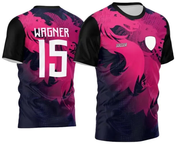 Camisa com dragão rosa em degradê sobre fundo preto e azul, mangas pretas, escudo branco no peito esquerdo e texto 'SOCCER'. Nas costas, nome WAGNER e número 15 em branco sobre o dragão degradê.