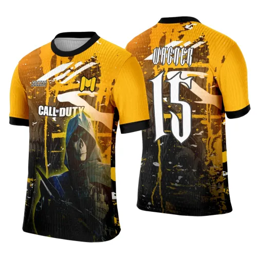 Camisa gamer nas cores amarela e preta, com personagem de caveira de capuz azul segurando arma na frente e o número 15 em destaque nas costas com a palavra VINCER acima, em design agressivo e moderno.