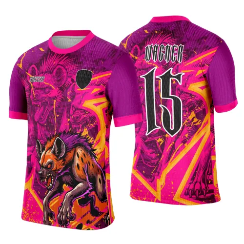 Camisa roxa com destaque na frente e nas costas para figura agressiva de hiena em tons laranja e rosa, mangas roxas com punho rosa, texto SOCCER à frente e número 15 com nome VICTOR nas costas
