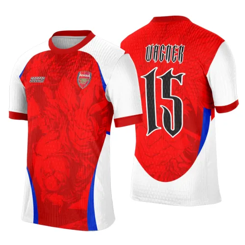 Camisa vermelha com mangas brancas e detalhes em azul, mascote dragão estilo anime no centro da frente junto ao escudo Arsenal e texto SOCCER, nas costas nome VICNER e número 15 em preto com borda branca sobre fundo vermelho e figura do dragão