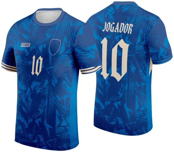 Camisa azul com estampa geométrica frontal e traseira, número 10 bege à frente e atrás, escudo branco vazado à esquerda do peito, texto SOCCER branco à direita, nome JOGADOR em estilo gótico atrás.