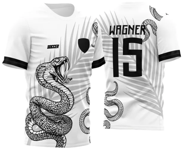 Camisa branca com estampa frontal de cobra branca detalhada em preto, fundo com folhas de palmeira cinza, texto 'SOCCER' e escudo preto na frente. Nas costas, nome 'WAGNER', número '15' e cobra entre folhas de palmeira cinza, mangas com faixas pretas.