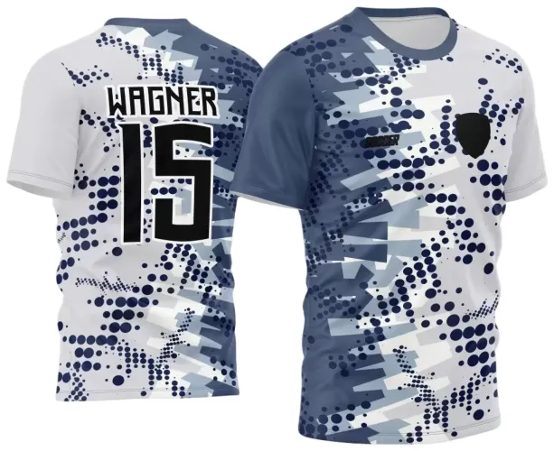 Camisa branca e azul com padrão geométrico azul escuro, cinza e branco na frente e costas. Frente tem escudo preto e texto 'SOCCER'. Nas costas, nome WAGNER e número 15 em preto com contorno branco.