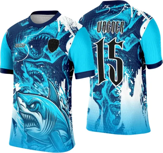 Camisa com estampa frontal de tubarão azul feroz e detalhes em ondas, mangas azul claro com punhos escuros. Nas costas, nome WAGNER e número 15 em preto com borda branca, fundo com ondas agitadas em tons de azul e branco.