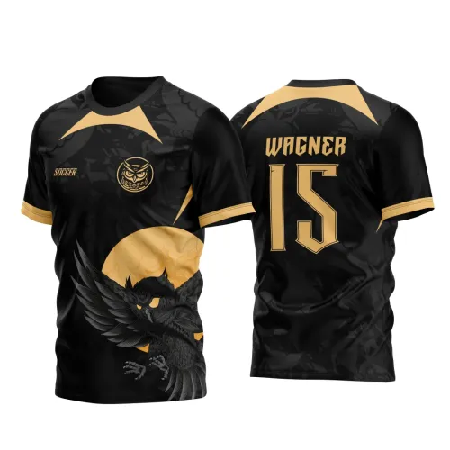Camisa preta com figura de coruja negra em destaque na frente sobre círculo dourado, texto 'SOCCER' e logo coruja; costas com nome WAGNER e número 15 em dourado, detalhes dourados em ombros e mangas.