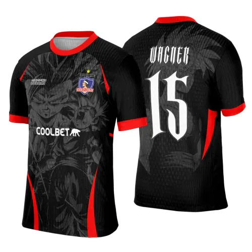 Camisa preta com detalhes vermelhos nas mangas, gola e laterais. Na frente, personagens de Dragon Ball em cinza escuro, escudo azul e vermelho 'COLO COLO' e textos 'SOCCER' e 'COOLBET'. Nas costas, nome 'WAGNER' e número 15 em branco sobre figura do personagem.