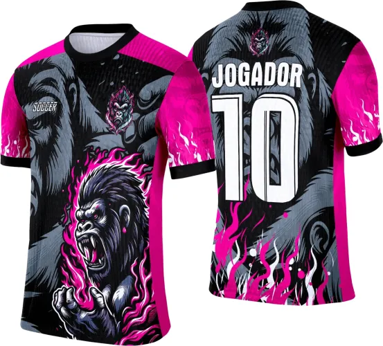 Camisa com desenho de gorila preto e cinza rodeado de chamas rosas na frente, fundo preto com detalhes rosa, manga rosa, texto Soccer; costas com rosto grande de gorila cinza, texto branco JOGADOR e número 10, gola e punhos pretos.