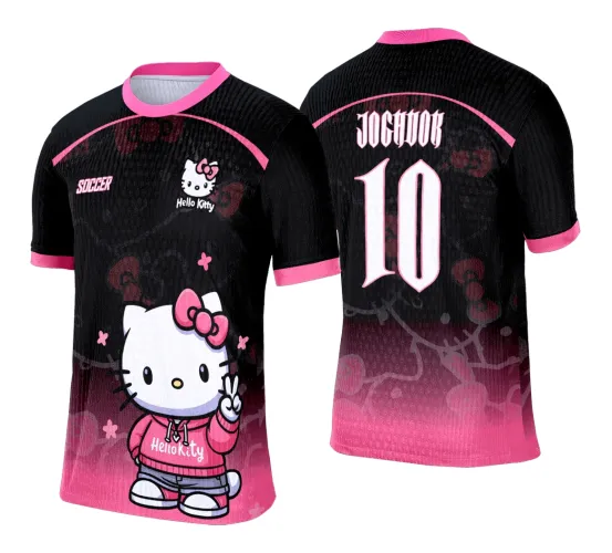 Camisa preta com detalhes em rosa, frente com Hello Kitty de moletom rosa fazendo sinal de paz e textos Hello Kitty e SOCCER; costas com número 10 grande e texto JOGADOR em rosa e branco, fundo com lacinhos rosa e degradê rosa na parte inferior.
