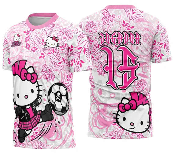 Camisa com estampa de Hello Kitty punk usando jaqueta preta e saia rosa, chutando bola de futebol com caveira na frente. Nas costas, número 15 rosa com texto JOGADOR e figura da Hello Kitty punk em fundo floral rosa.