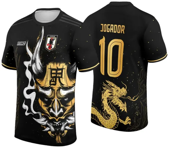 Camisa preta com máscara japonesa dourada e branca na frente, escudo JFA e texto SOCCER, costas com dragão dourado, número 10 e texto JOGADOR em dourado.