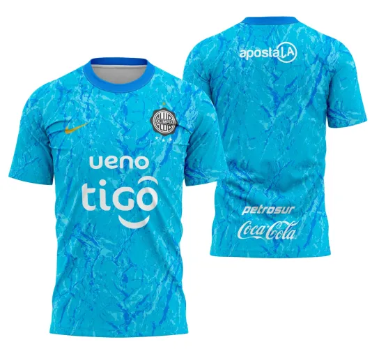 Camisa azul claro com estampa marmorizada azul escuro, escudo do Olimpia preto e branco no peito, Nike amarelo, logos brancos 'ueno tigo' na frente e 'aposta.LA', 'petrosur', 'Coca-Cola' nas costas, gola azul royal.