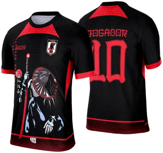 Camisa preta com detalhes vermelhos, frente com personagem japonês com chapéu cônico e cajado, texto 'SOCCER' e caracteres japoneses, escudo 'JAPAN JFA', costas com 'JOGADOR' e número 10 em vermelho.