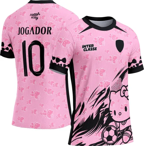 Camisa rosa com estampa grande da Hello Kitty segurando bola de futebol na frente e fundo com padrões pequenos da Hello Kitty, textos INTER CLASSE frontal e JOGADOR 10 nas costas em preto, detalhes em preto nos punhos, ombro e laterais.