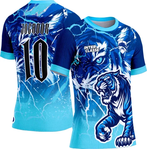 Camisa com visual azul intenso e azul claro, frente com tigre feroz nos detalhes e fundo com raios, costas com nome JOGADOR e número 10, mangas e gola na cor azul clara.