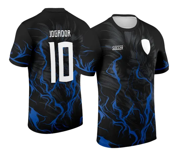 Camisa preta com estampa de leão sombreado e chamas azuis na frente, escudo branco sem texto e a palavra SOCCER, costas com texto JOGADOR acima do número 10 em branco, detalhes azuis nas mangas.