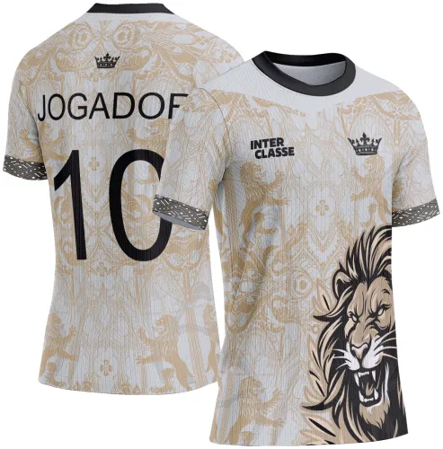 Camisa com grande rosto de leão dourado na frente, fundo branco com padrão dourado e textos INTERCLASSE e coroa preta. Nas costas, nome JOGADOF, número 10 em preto e detalhes heráldicos dourados com faixas pretas nas mangas.