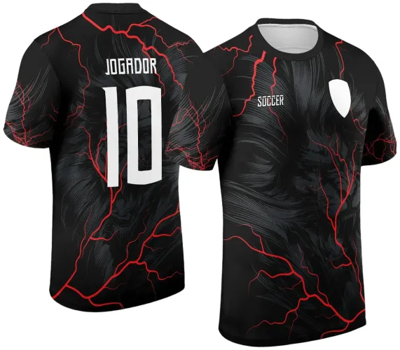 Camisa preta com estampa frontal e traseira de leão estilizado em cinza escuro, detalhes de raios vermelhos, escudo branco na frente e texto 'SOCCER'. Nas costas, número 10 e 'JOGADOR' em branco.