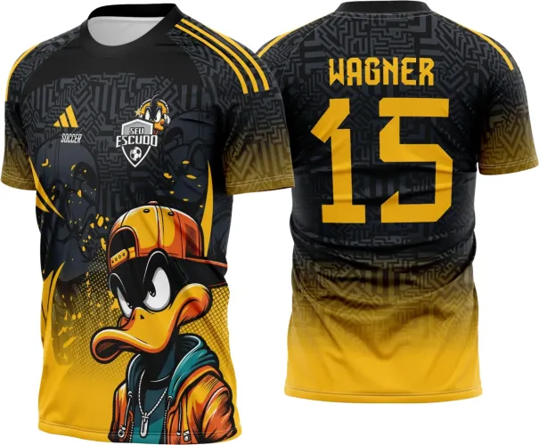 Camisa com pato cartoon enfocado na frente usando boné amarelo e jaqueta laranja, fundo preto com detalhes gráficos. Nas costas, degradê preto para amarelo com nome WAGNER e número 15 em amarelo grande.