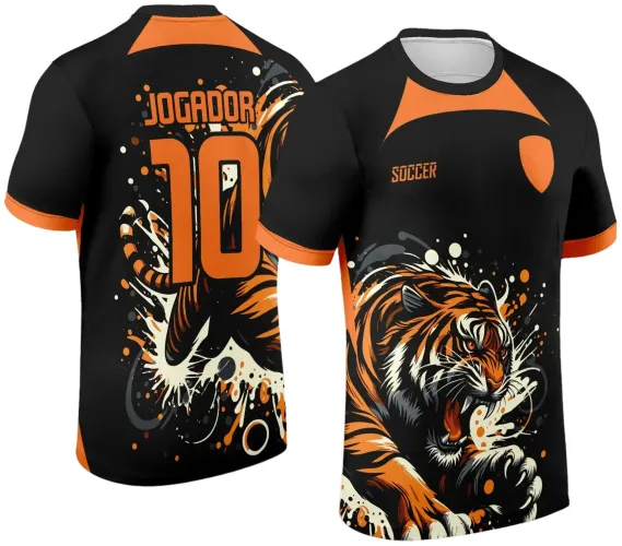 Camisa preta com detalhes laranja, frente apresenta tigre agressivo com boca aberta, texto 'SOCCER' e escudo laranja; costas mostram tigre em movimento com texto 'JOGADOR' e número 10 em laranja.