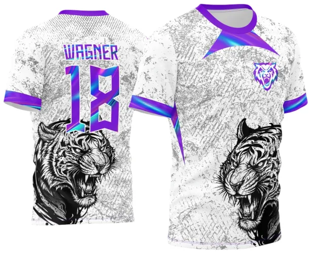Camisa branca com textura cinza e estampa de tigre preto agressivo na frente e nas costas. Detalhes em degradê roxo e azul nas mangas, gola, nome WAGNER e número 18 nas costas, além de escudo de tigre roxo no peito.