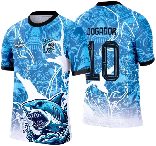 Camisa com figura principal de tubarão azul agressivo na frente, fundo degradê azul e branco com detalhes em ondas brancas; costas exibem tubarão estilizado, texto JOGADOR e número 10 em preto, gola e punhos também pretos.