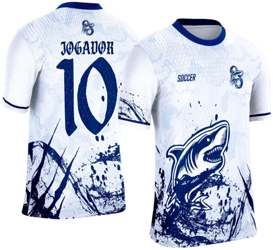 Camisa branca com gola e punhos azuis, frente com tubarão em pose agressiva com detalhes de respingo em azul escuro e texto Soccer, costas com número 10 grande e texto JOGADOR acima, além do mascote pequeno na nuca e detalhes splash azul.