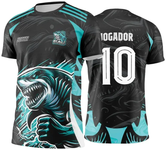 Camisa preta com grande estampa frontal de tubarão em pose agressiva nas cores azul-turquesa e branco, texto 'SOCCER' e mascote 'SHARK' no peito; costas exibem número 10 branco e texto 'JOGADOR' em branco sobre sombra do tubarão.