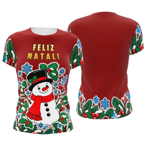 Camisa estampada por inteiro com fundo vermelho, boneco de neve sorridente na frente, galhos, folhas verdes, azevinhos, flocos de neve azuis e a frase FELIZ NATAL no peito.