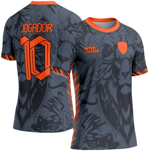Camisa escolar cinza escuro com leão estilizado em tons de cinza e preto na frente, detalhes laranja na gola e mangas, texto INTER CLASSE na frente e costas com nome JOGADOR e número 10 em laranja brilhante.