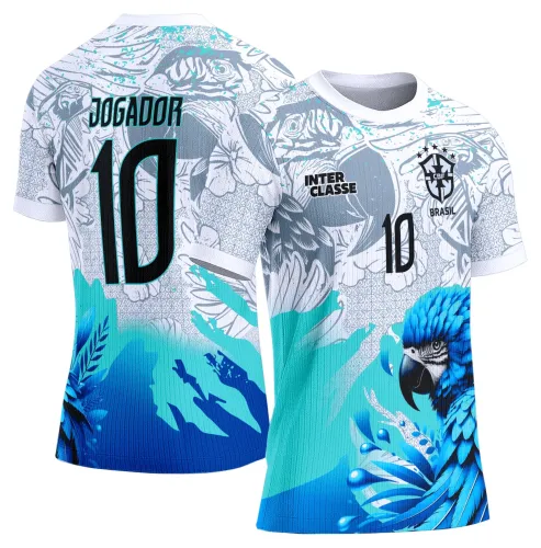 Camisa com estampa frontal de papagaio azul vibrante, fundo turquesa e cinza com detalhes florais. Costas exibem nome JOGADOR e número 10 em preto, além de elementos gráficos em azul e cinza claro.