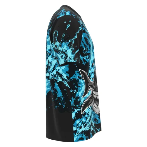 Camisa totalmente estampada com tema de tubarão, fundo preto com efeitos de água azul vibrante, tubarão estilizado na frente e detalhes de respingos em todas as partes, incluindo mangas e costas.