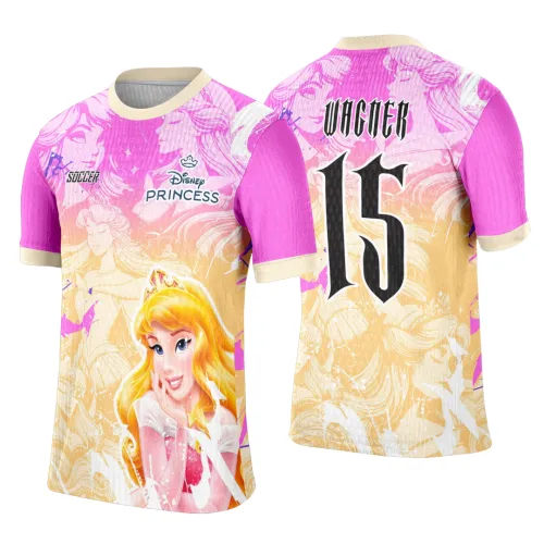 Camisa feminina com frente em degradê rosa e bege mostrando princesa loira sorridente e textos Disney PRINCESS e SOCCER, costas rosas com número 15 preto e nome VAGNER destacando tema floral suave.