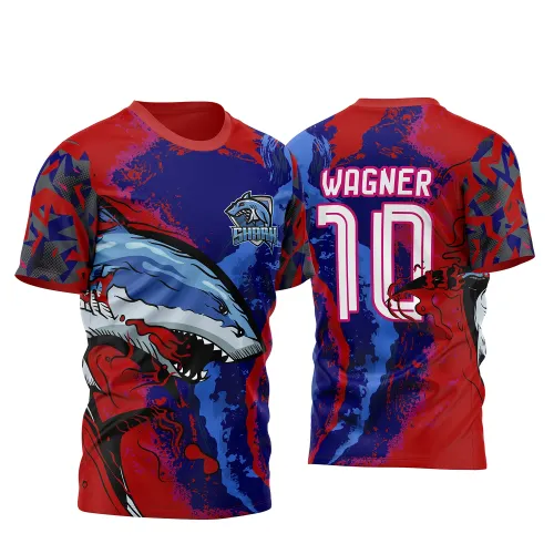 Camisa vibrante com frente exibindo um tubarão agressivo em tons de azul e branco sobre fundo vermelho e azul, com logotipo Shark no peito. Nas costas, nome Wagner e número 10 em branco com contorno rosa sobre degradê vermelho e azul intenso.